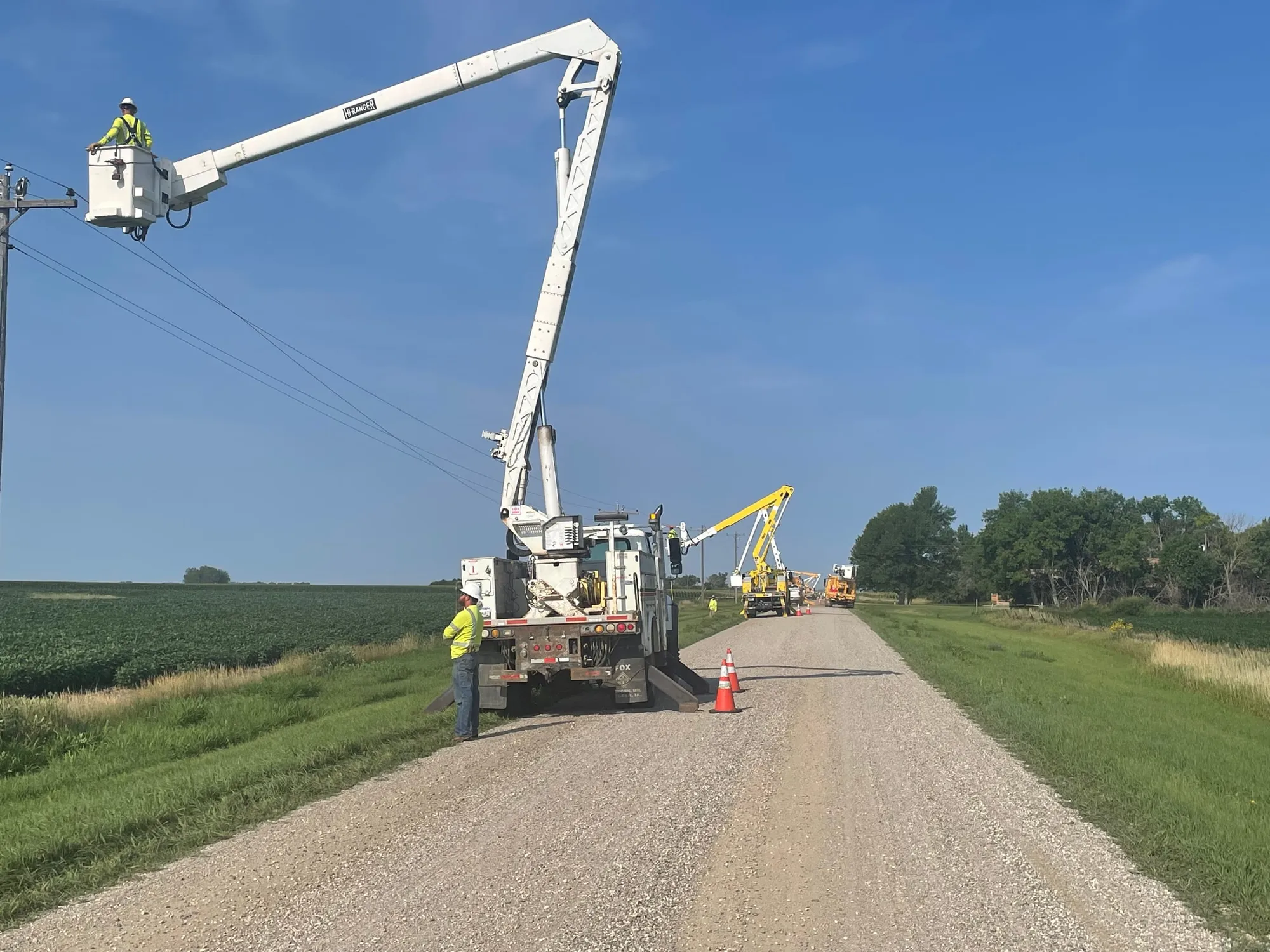 Two Karian Peterson bucket crews working the same span of line on a gravel township road